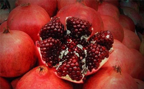 лежит много гранатов и один из них разрезан дольками